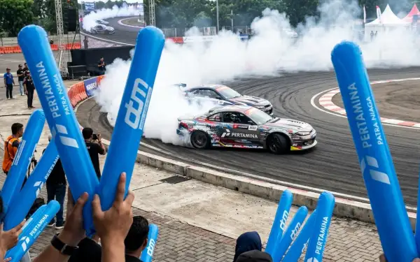 Penonton menyemarakkan acara drift mobil menggunakan Balon Tepuk Balangan berwarna biru.