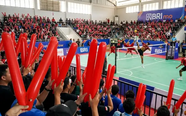 Balon tepuk Batang berwarna merah digunakan penonton untuk menyemangati pertandingan sepak takraw di dalam gedung olahraga.