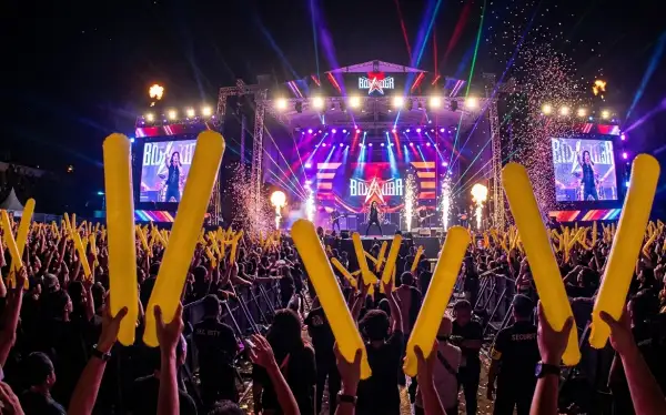 Penonton menikmati kemeriahan konser musik dengan panggung penuh lampu.