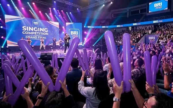 Penonton memberikan semangat kepada peserta kompetisi menyanyi di atas panggung.