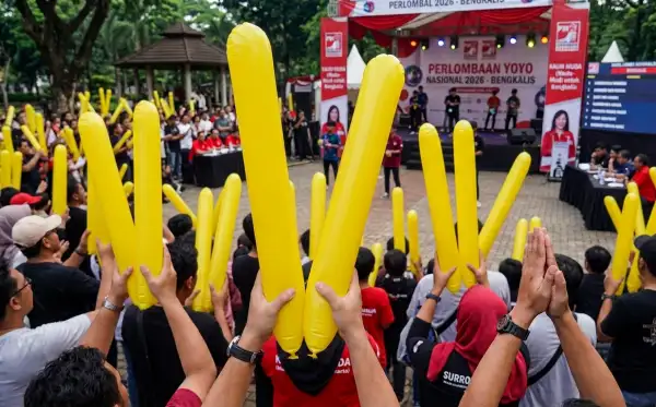 Penonton mengangkat balon kuning sambil menyaksikan perlombaan permainan yoyo dalam suasana acara yang meriah.