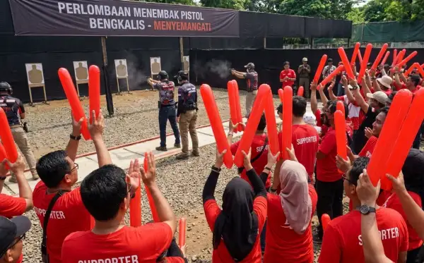 Suporter berbaju merah menyaksikan perlombaan menembak pistol di Bengkalis.