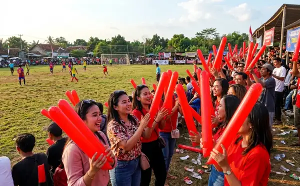 Suporter memberikan semangat pada pertandingan sepak bola di lapangan desa.