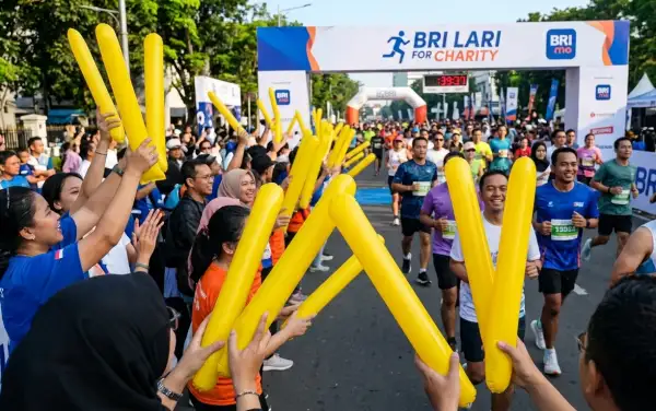 Penonton menyemangati peserta yang mengikuti lomba lari di area jalan raya.