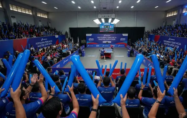 Penonton mengibarkan balon tepuk biru saat menyaksikan pertandingan tenis meja Pertamina Master Open di dalam GOR.