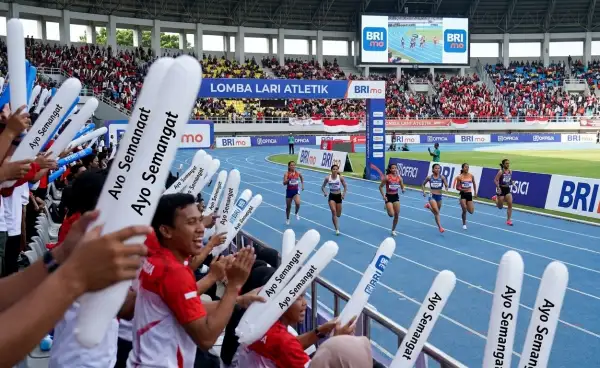 Penonton mengangkat balon tepuk putih bertuliskan βAyo Semangatβ saat mendukung peserta lomba lari.