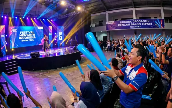 Penonton mengangkat balon tepuk Kampar berwarna biru untuk memberikan semangat pada final Festival Menyanyi Indonesia di atas panggung.