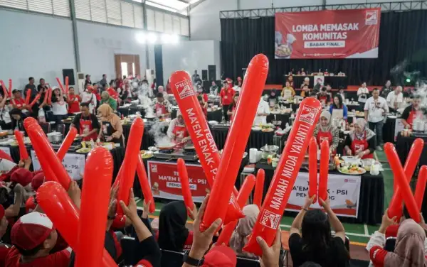 Suporter memeriahkan lomba memasak komunitas dengan balon tepuk merah saat peserta menyelesaikan babak final.