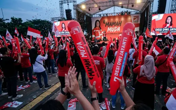 Peserta kampanye membawa balon tepuk merah sebagai media promosi acara.