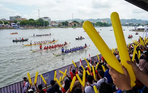 Penonton perlombaan dayung memberikan dukungan kepada perserta lomba