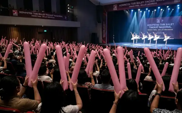 Penonton membawa balon tepuk berwarna merah muda untuk memeriahkan pertunjukan tari balet di auditorium