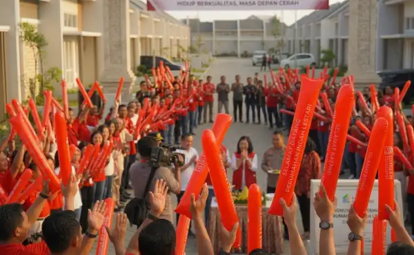 Peserta acara peresmian perumahan mengangkat balon tepuk berwarna merah sambil mengikuti kegiatan bersama.