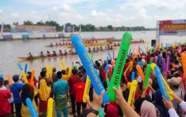 penonton sedang menyemangati untuk peserta lomba perahu di tepi danau.