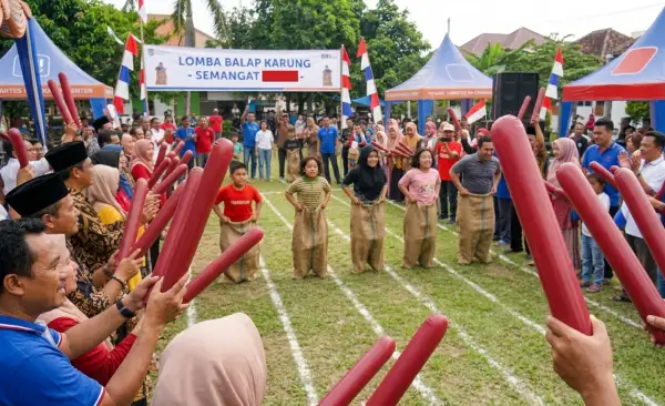 penonton memegang balon tepuk saat mengikuti lomba balap karung di lapangan