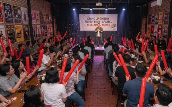 Penonton menikmati pertunjukan stand up comedy di sebuah kafe dengan suasana hangat dan meriah.