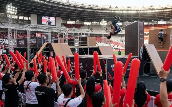 Balon tepuk merah memeriahkan perlombaan parkour yang disaksikan ratusan penonton di stadion.