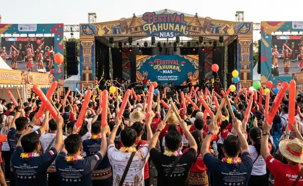 Penonton mengangkat balon tepuk berwarna merah saat meramaikan Festival Tahunan Nias