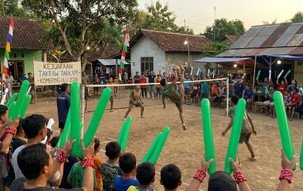 Warga membawa balon tepuk hijau untuk memberikan semangat dalam pertandingan sepak takraw tarkam di desa.