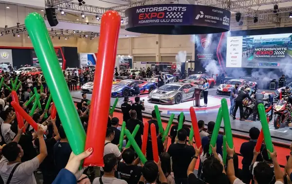 Pengunjung mengangkat balon tepuk merah dan hijau saat memeriahkan pameran mobil dan motor sport.