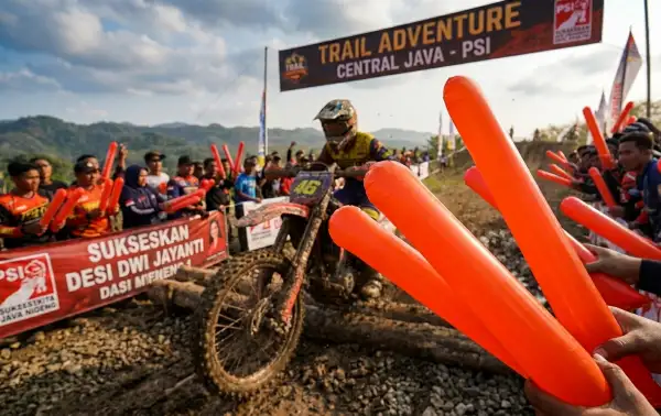 Penonton menggunakan balontepuk ogan komering ulu untuk menyemangati pembalap motor trail di lintasan berlumpur.