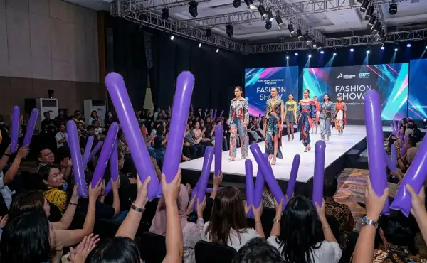 Balon tepuk Palembang berwarna ungu diangkat penonton saat menikmati pertunjukan fashion show.