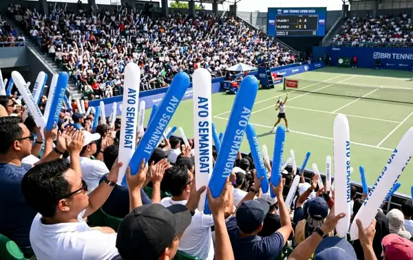 Penonton sedang menyaksikan pertandingan tenis lapangan.