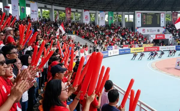 Penonton menyaksikan perlombaan sepatu roda di arena olahraga.