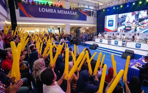 Penonton mengangkat balon tepuk saat acara lomba memasak