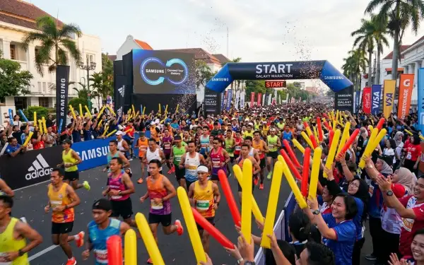 Suasana meriah event marathon dengan peserta berlari dan penonton memberikan semangat.