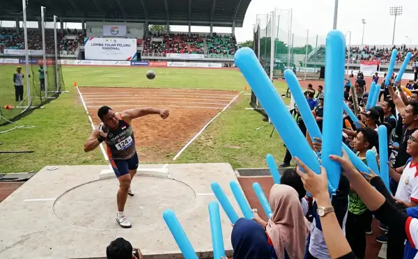 Balon tepuk tanah datar digunakan penonton untuk memberikan semangat pada perlombaan tolak peluru di area stadion.