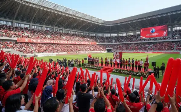 Penonton mengangkat balon tepuk tanah datar berwarna merah saat acara peresmian stadion baru Tanah Datar berlangsung.
