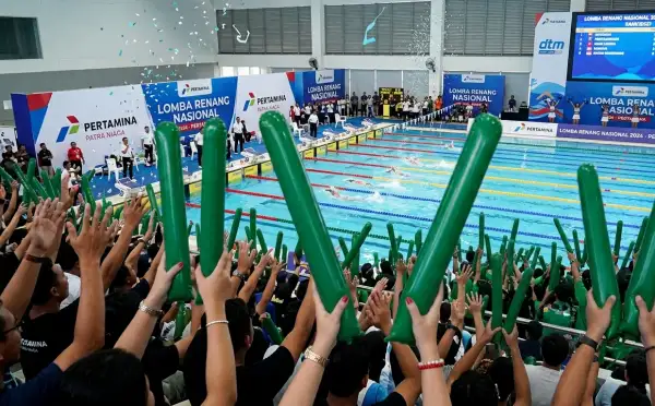 Penonton sedang menyaksikan pertandingan renang di dalam arena.