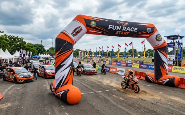 Gerbang balon berdesain sporty sebagai pintu start acara fun race dengan mobil dan motor di area perlombaan.