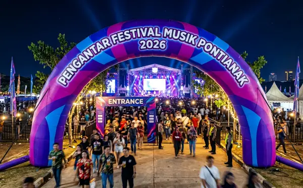 Gerbang balon berwarna ungu dengan pencahayaan meriah sebagai pintu masuk festival musik malam hari.
