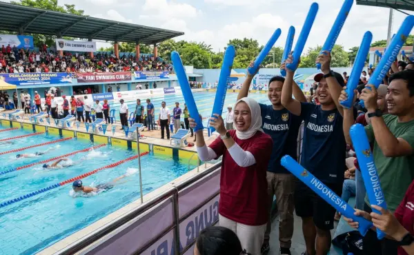Penonton lomba renang menyemangati atlet di arena pertandingan.