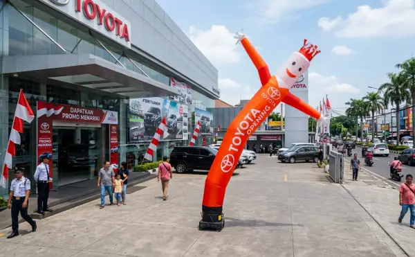 Sky dancer berwarna merah dan oranye di depan showroom Toyota sebagai media promosi untuk menarik perhatian calon pembeli mobil.